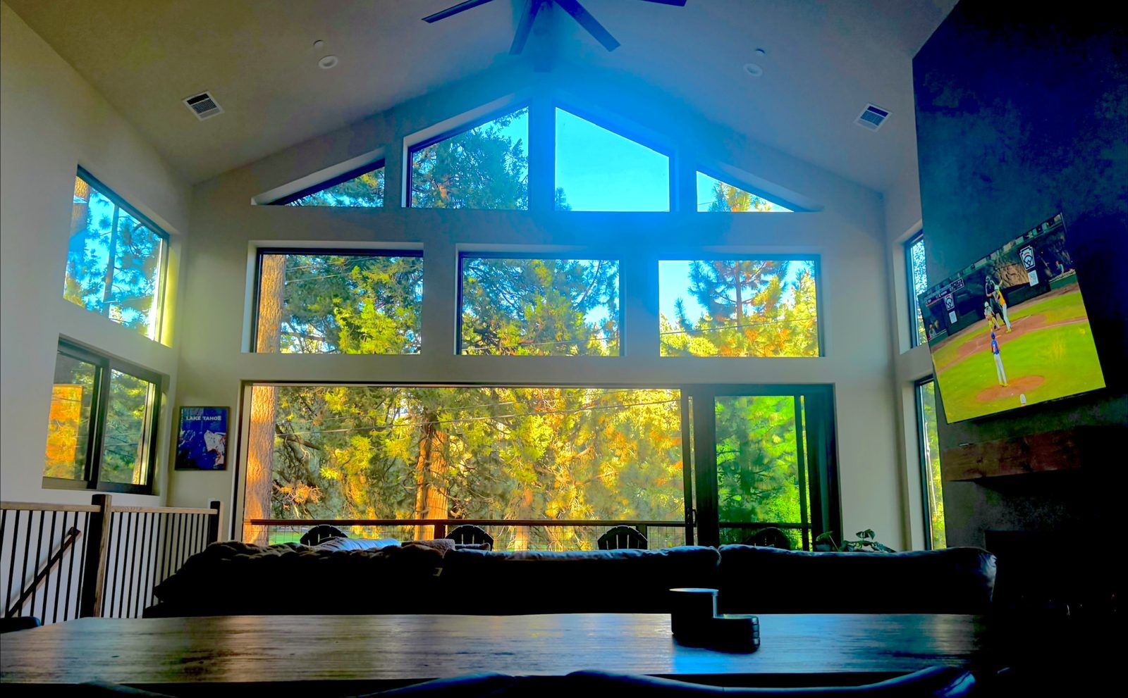 Vaulted great room with a wall of windows looking into sunlit pines