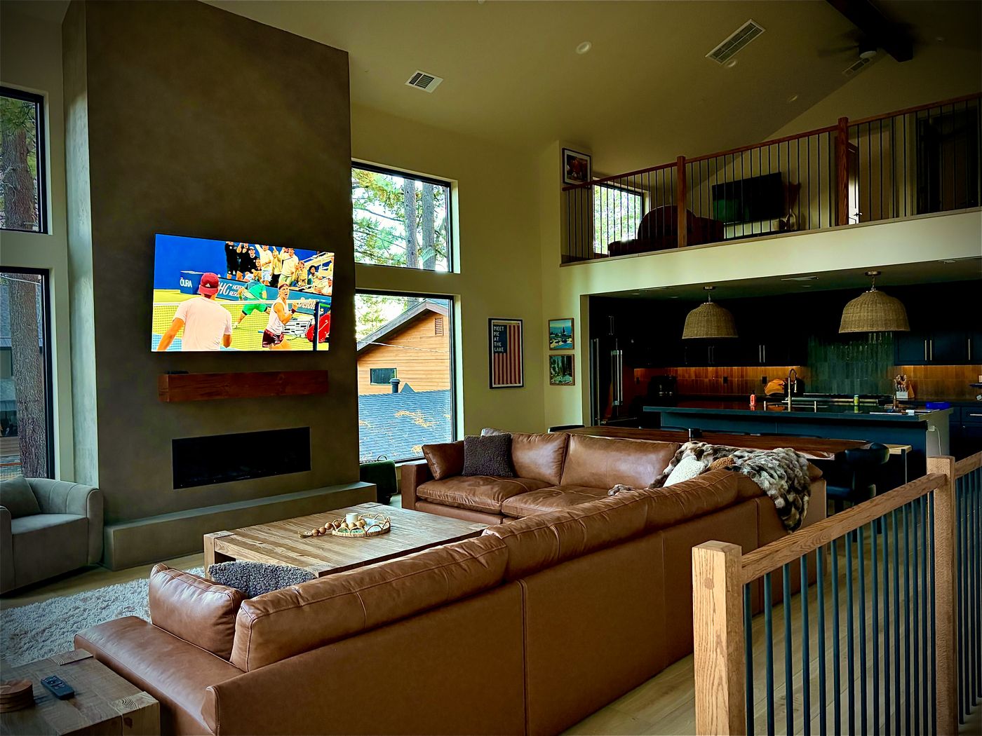 Great room with leather sectional, concrete fireplace, and open kitchen beyond